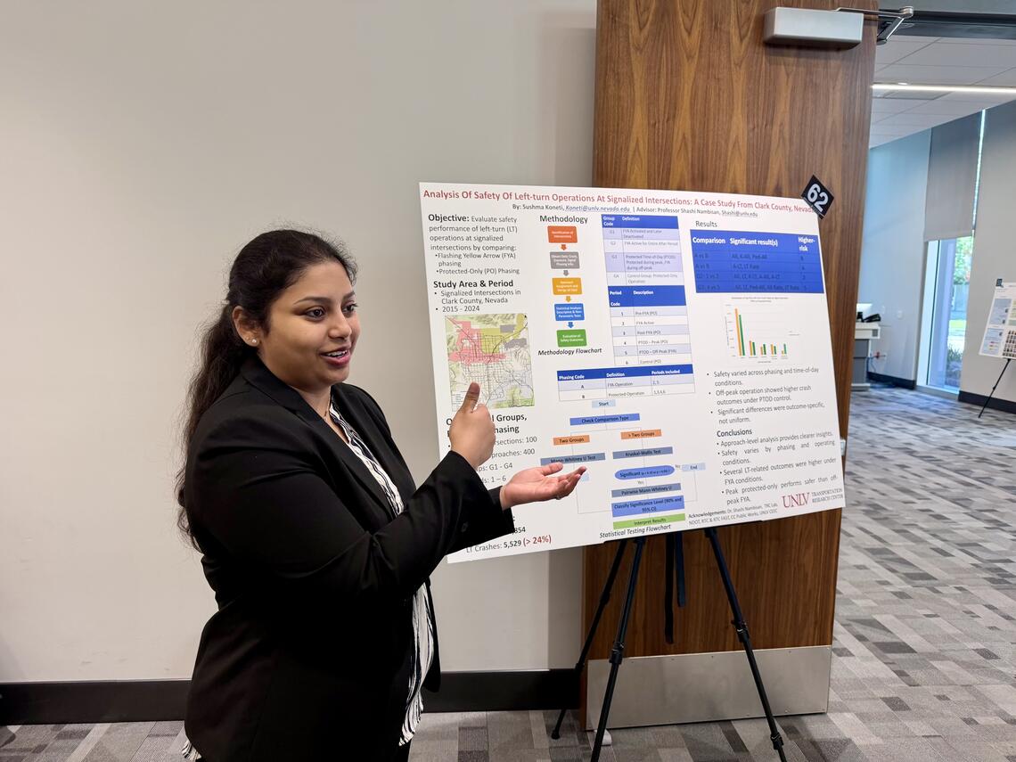 A student gestures toward her research poster