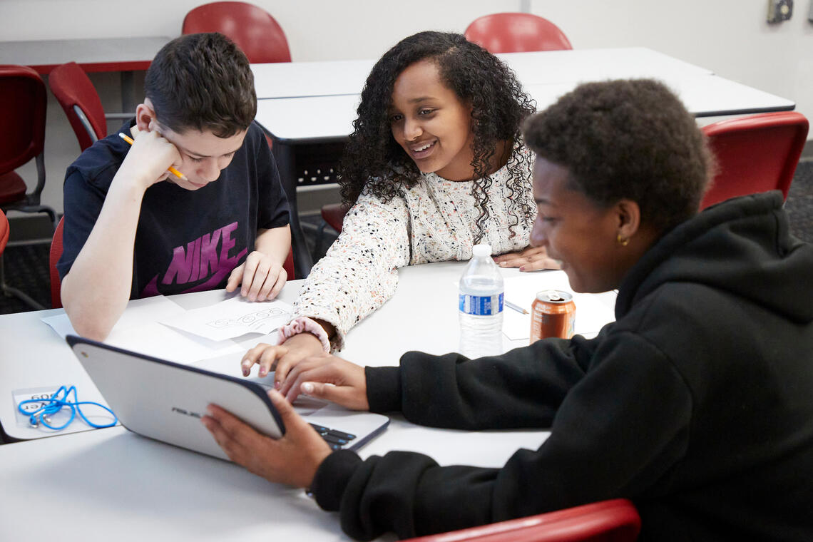 Three elementary-aged kids looking at a laptop computer
