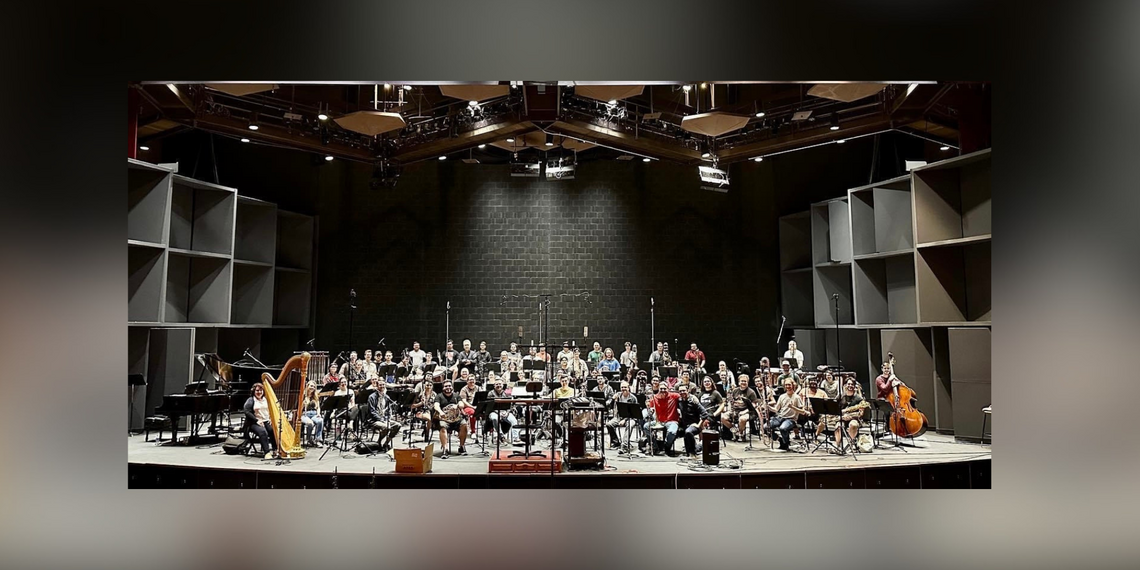 An orchestra on stage posing for a group picture