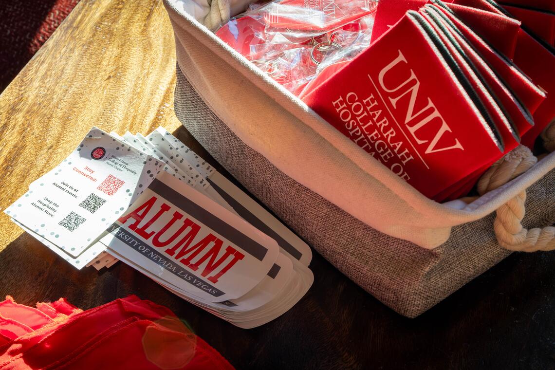 A close-up photo of U-N-L-V merch in a square fabric basket and stickers on a yellow table cover