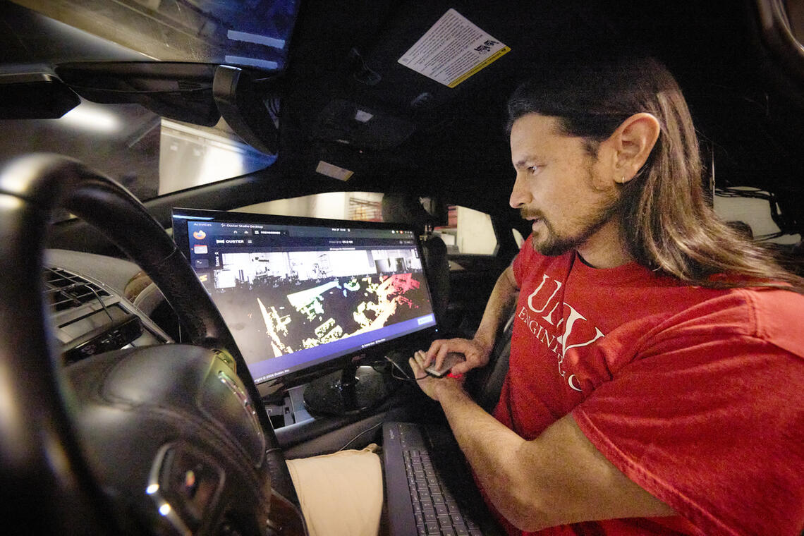 A man in a car with a computer monitor