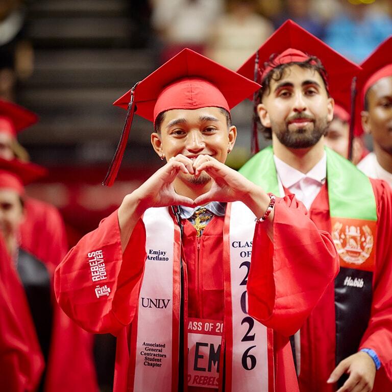 Graduate makes heart sign with hands