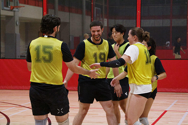 A group of five students huddled close on the court during their game.