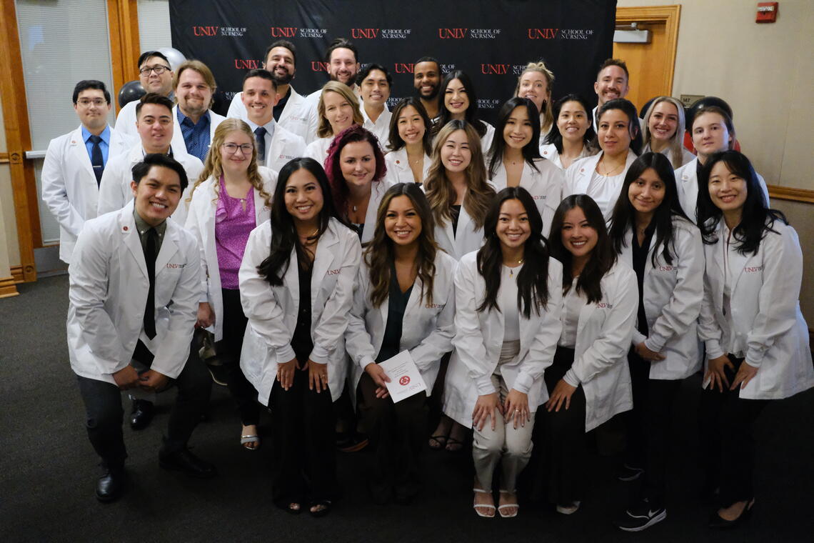 UNLV Nursing graduate students pose with their white coats during a special ceremony.