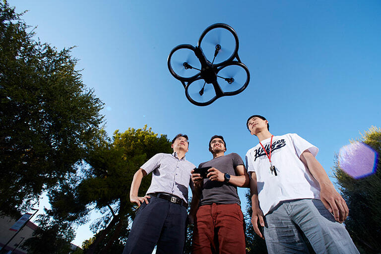 Students on campus using a remote controlled aerial drone.