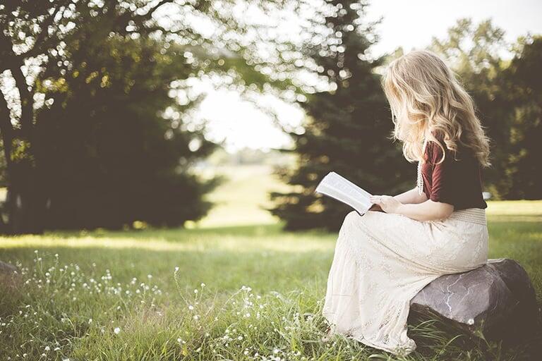 A woman reading a book outside.