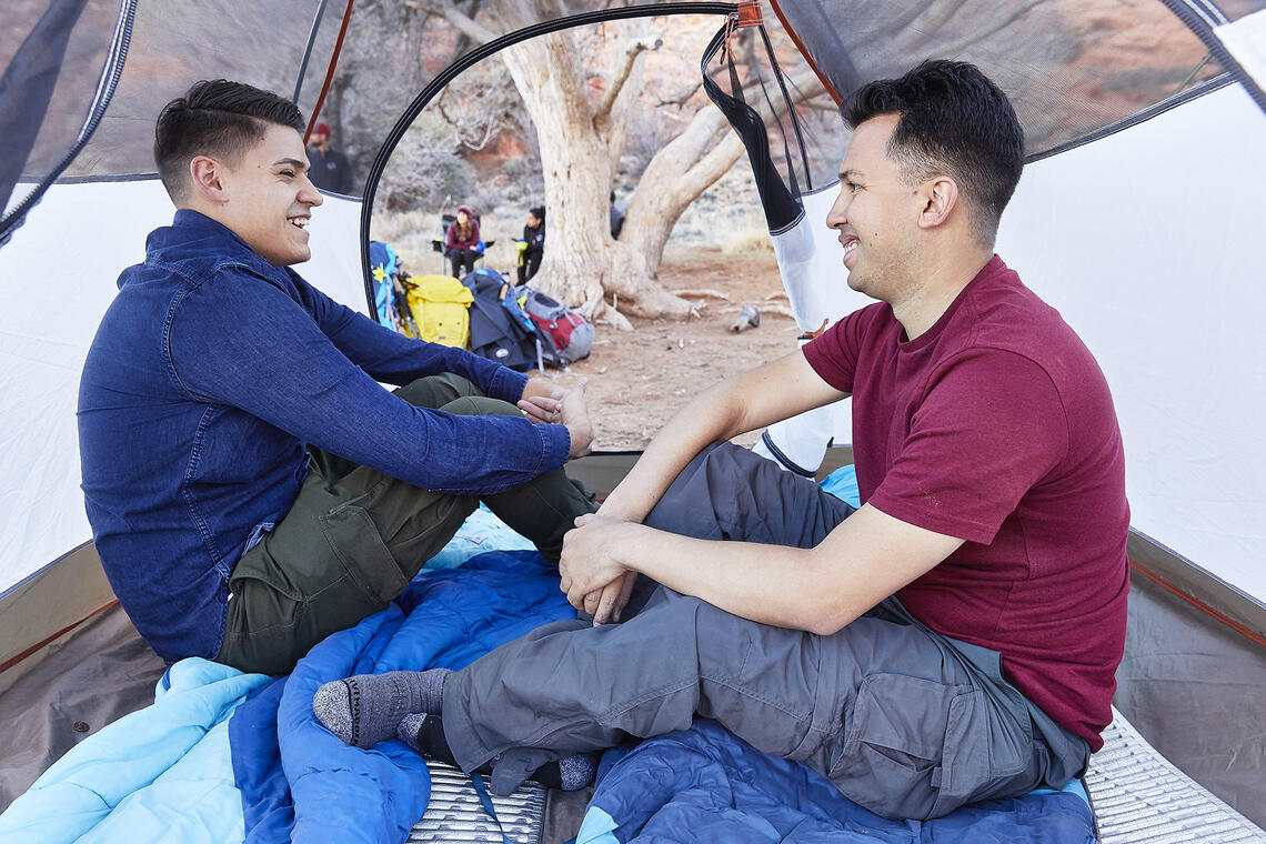 Two men sitting in a tent.