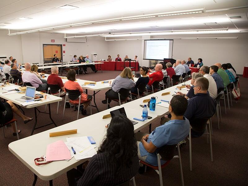 A large curriculum committee meeting with faculty members around the room.