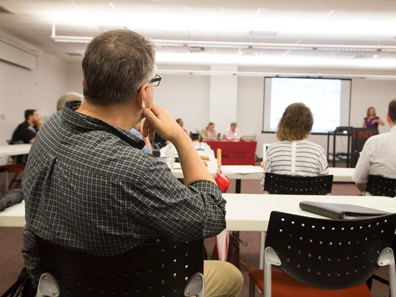 A faculty senate member reviewing information presented by a projector.