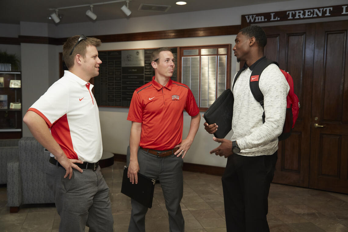 Three men standing and talking