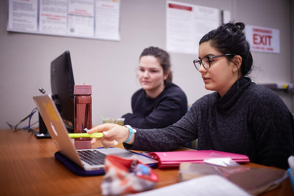 Two women looking over a computer together.