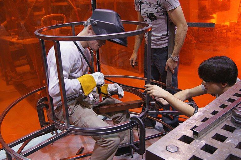 Three students working on a large metal structure