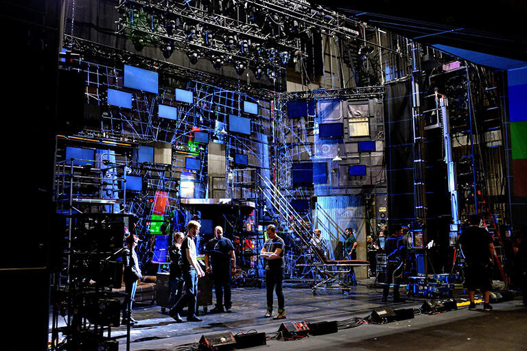 Three men standing on a set.