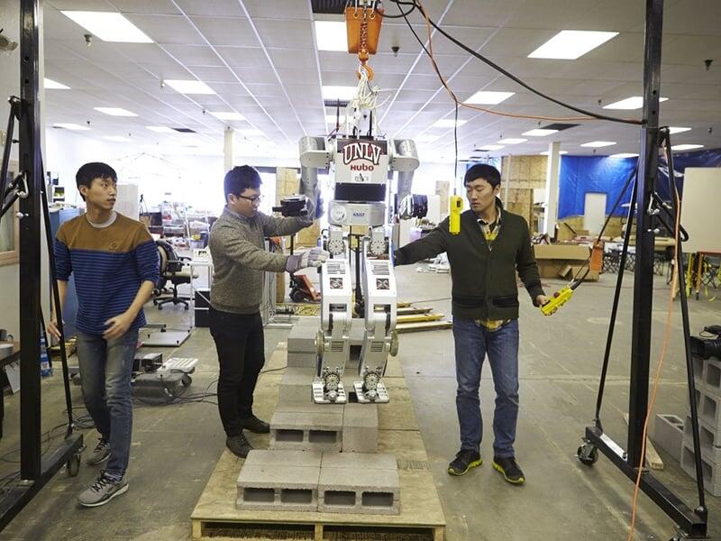 Three male students constructing a robot