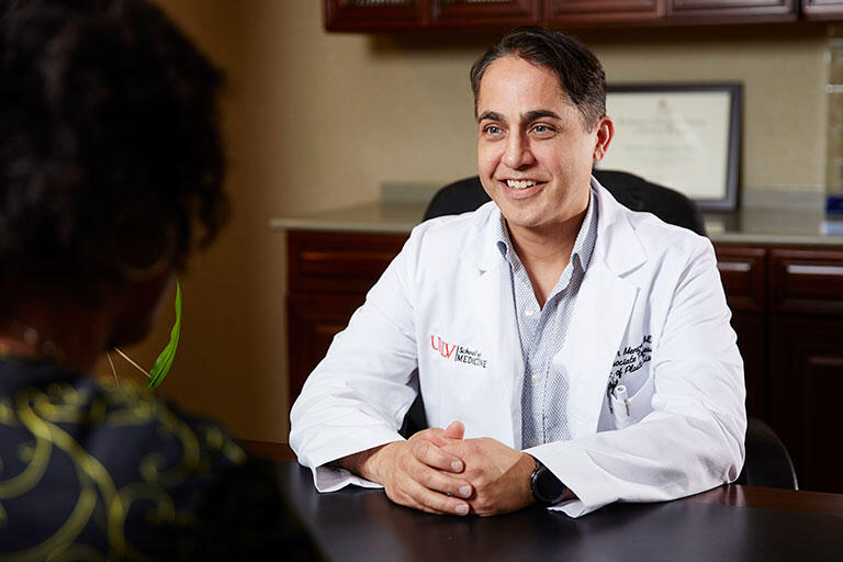 John Menezes, M.D., Associate Professor of Plastic Surgery, talking to a patient