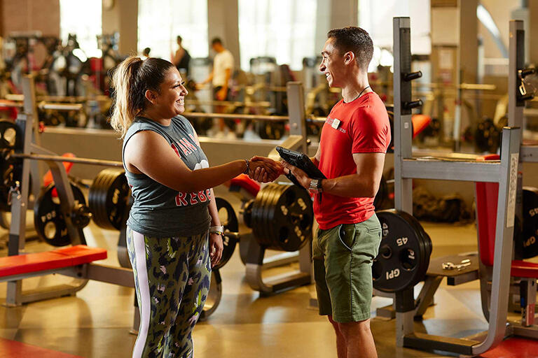Personal trainer shakes hands with client.