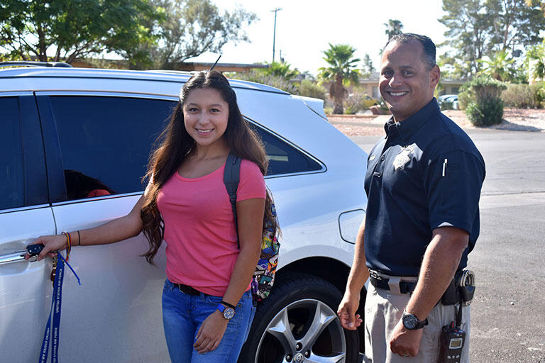 A girl and an officer next to a car