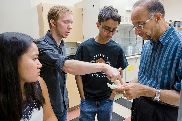 Graduate students looking at an object.