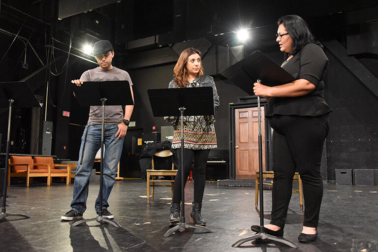 Three students standing on a stage