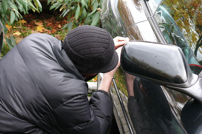 Person dressed in black trying to break into a car