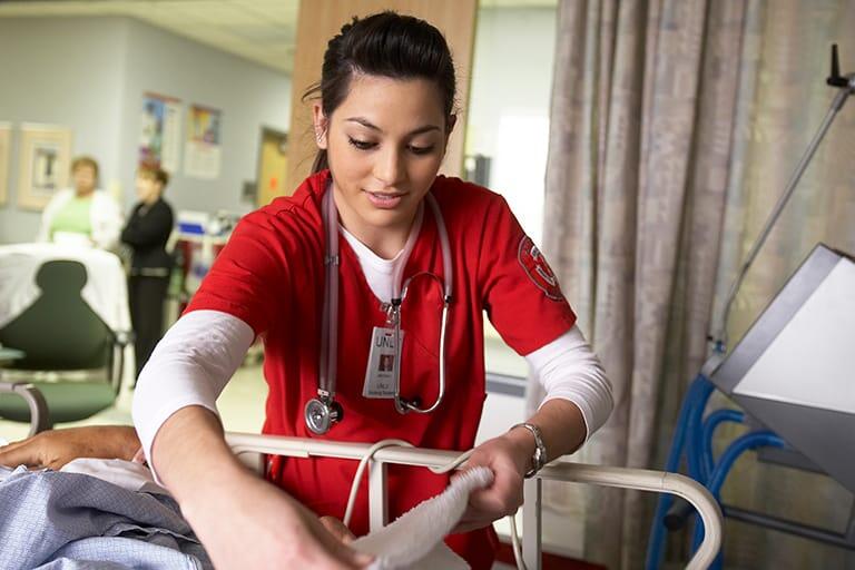Female nursing students working on a simulation dummy in a hospital bed