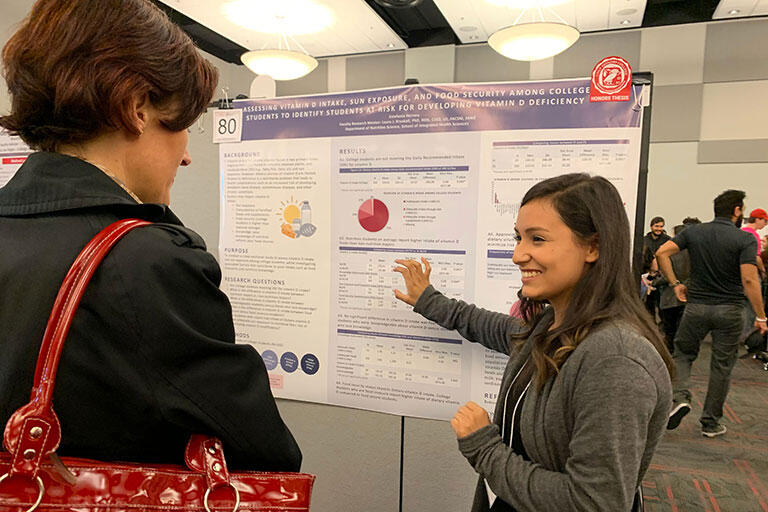 A student presenting her research poster