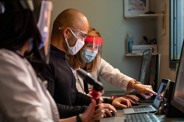 An instructor pointing at a computer screen for a medical student.