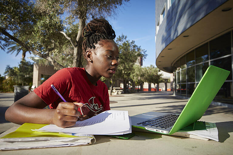 Student working outside on their laptop.