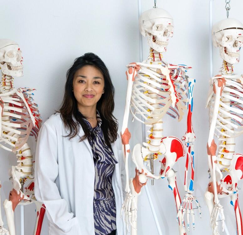 A woman standing in front of model skeletons.