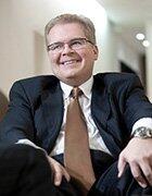 Paul Curtis Steelman smiling and sitting down in a suit