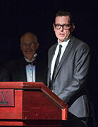 Tim Bavington in a suit standing behind a wooden podium