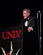Gary Nelson standing on a UNLV stage wearing a tuxedo