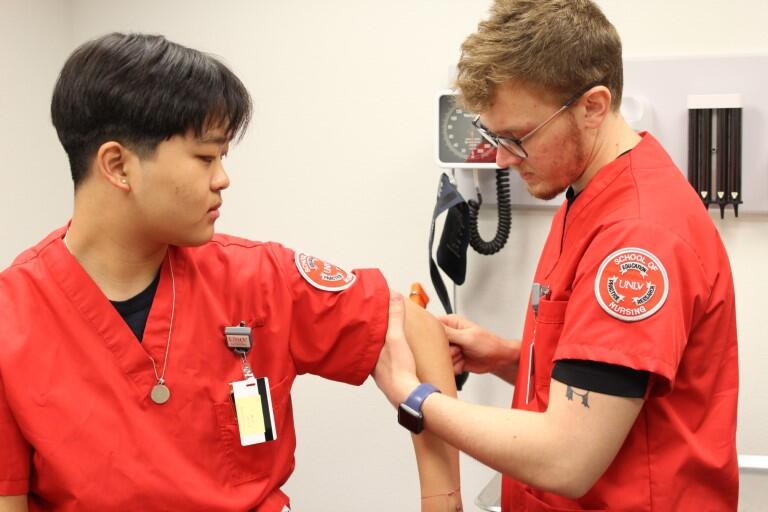 Nursing student hold other students arm