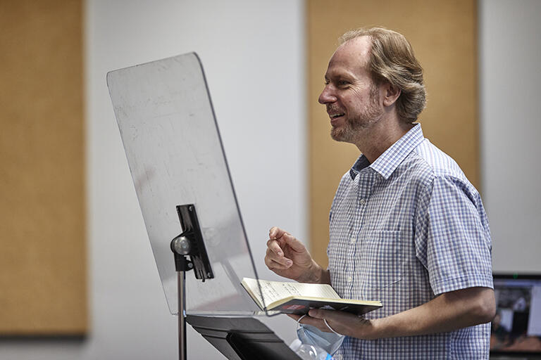Professor holding an open book during a lecture or presentation