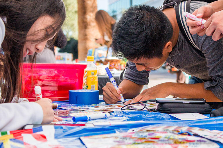 Two students using markers to help design a creative project.