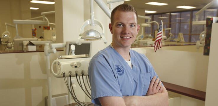 Dental school student poses by equipment