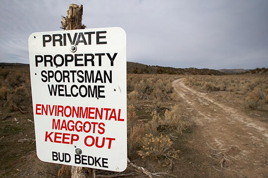 A sign in desert that reads "Private property. Sportsman welcome. Environmental maggots keep out. Bud Bedke"