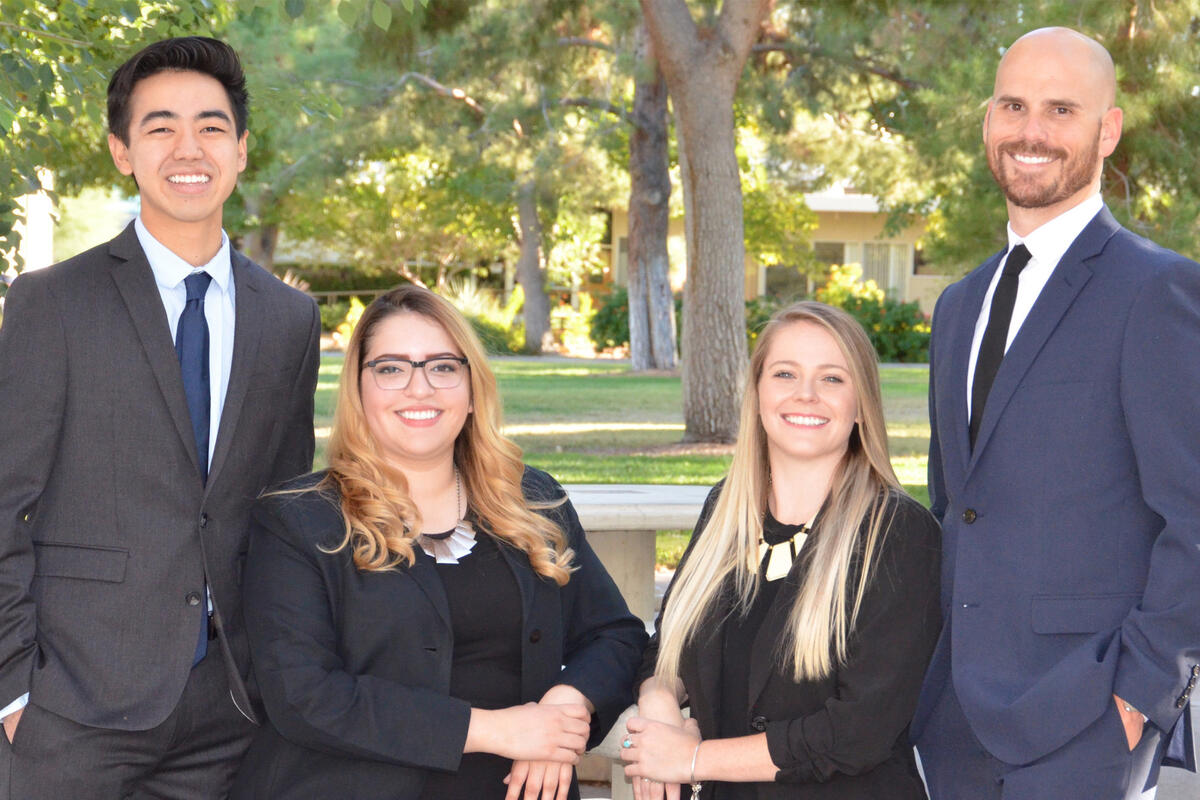 Two men stand flanking two seated women