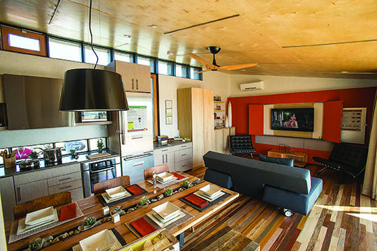 Inside of a smart desert home with furniture of a tv, couch, lamp, kitchen