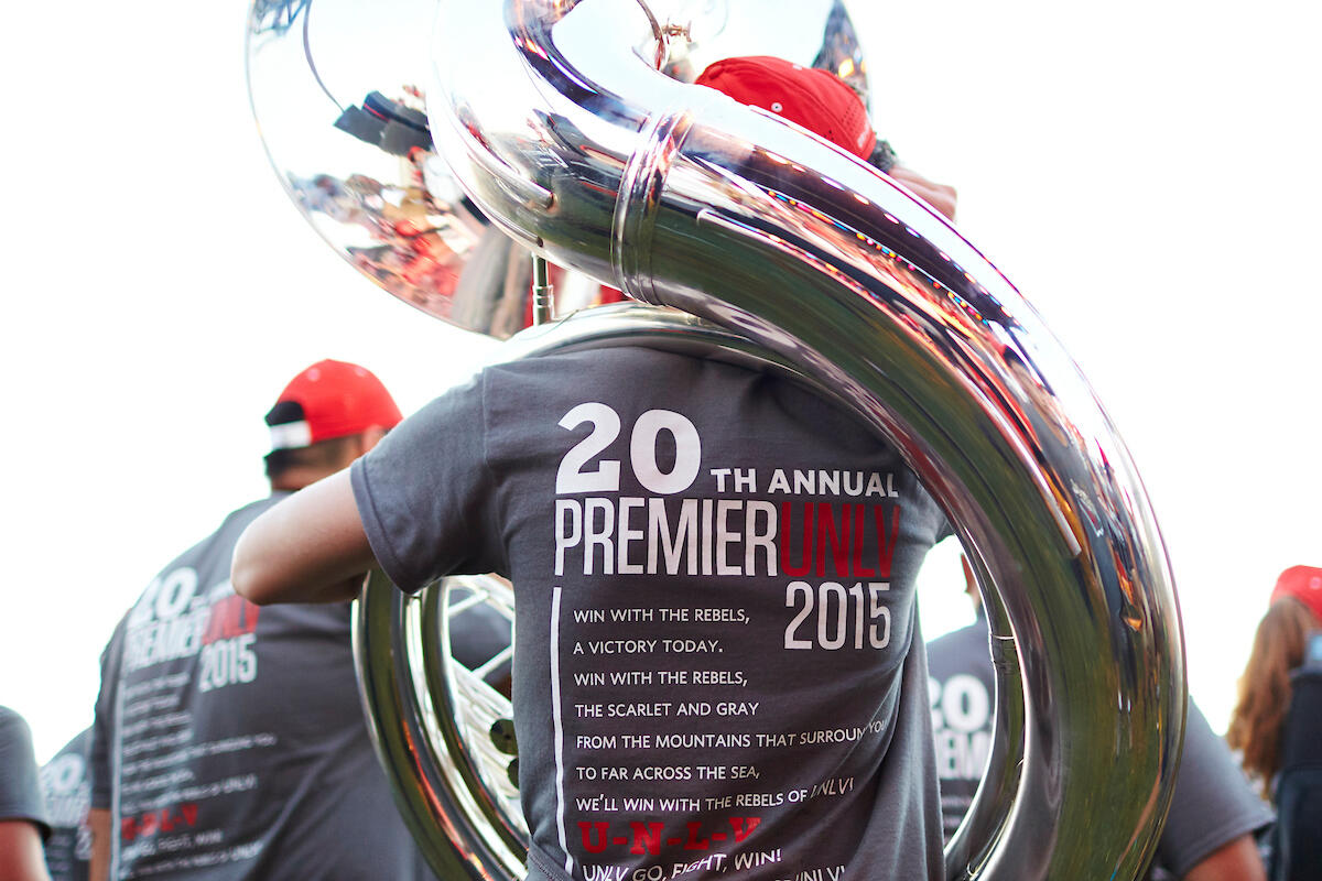 student with back to camera displays Premier 2015 shirt while holding tuba