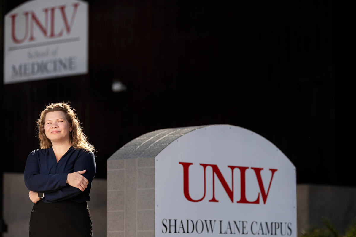 Cyndi Backstrom, a manager of IT Support Services Poses in front of UNLV sign.