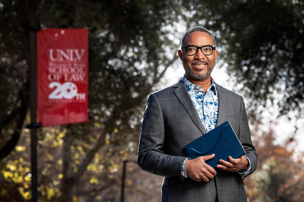 A portrait of law professor Frank Rudy Cooper standing outside on campus