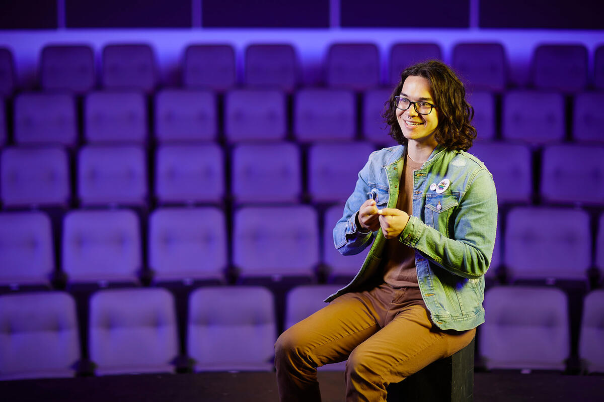 Karsyn Wilson sitting on stage in an empty theater.