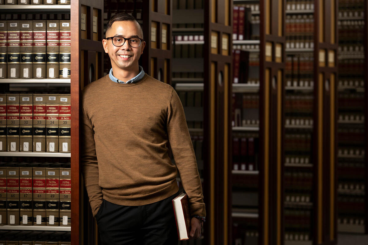 Pete Reyes poses next to a bookshelf.