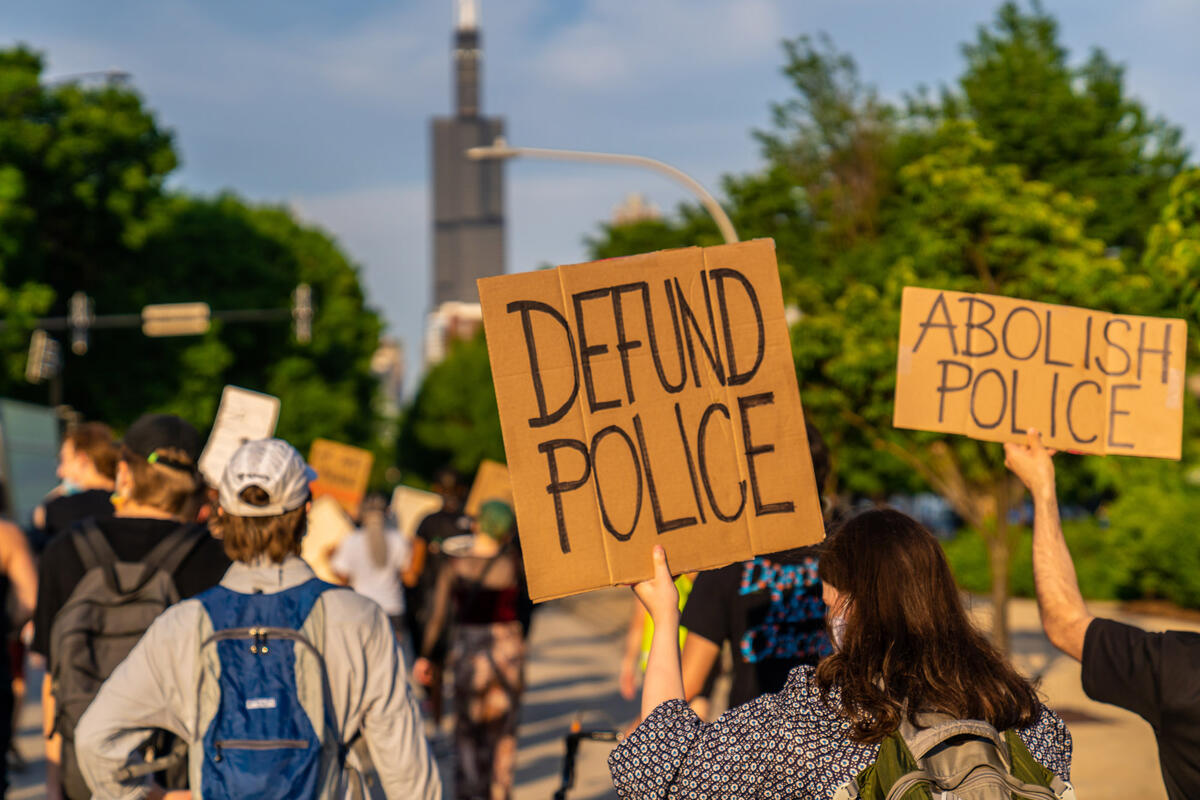 Protest signs read "Defund Police" and "Abolish Police"