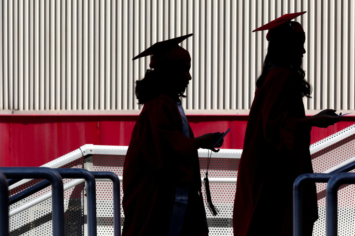 Two students in commencement regalia are seen in silhouette