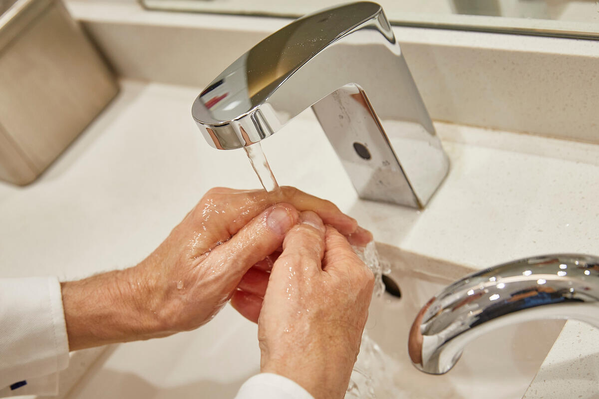 A man washes his hands in a bathroom sink