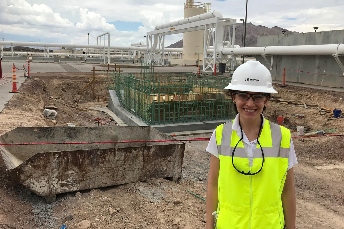 A woman in protective equipment stands at a construction site