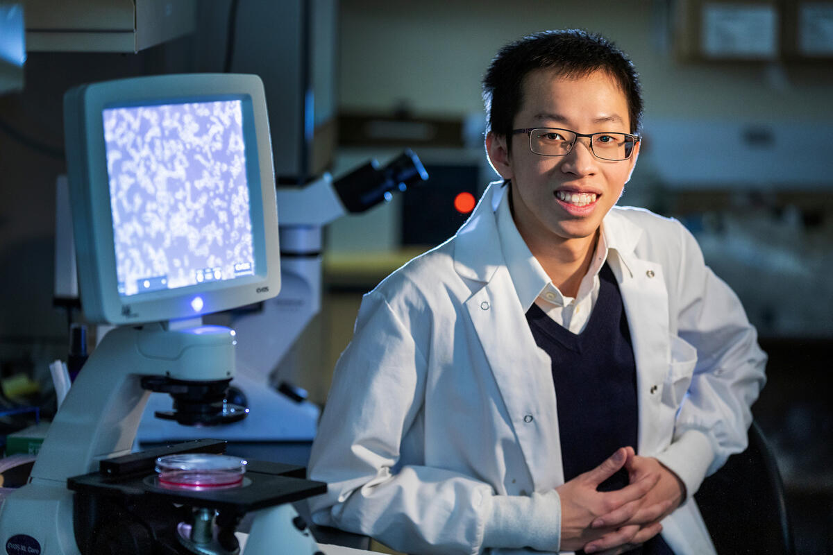 A man in a labcoat sit near a computer