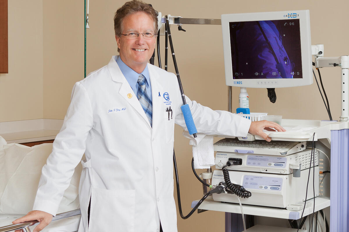 A doctor stands next to a piece of medical equipment